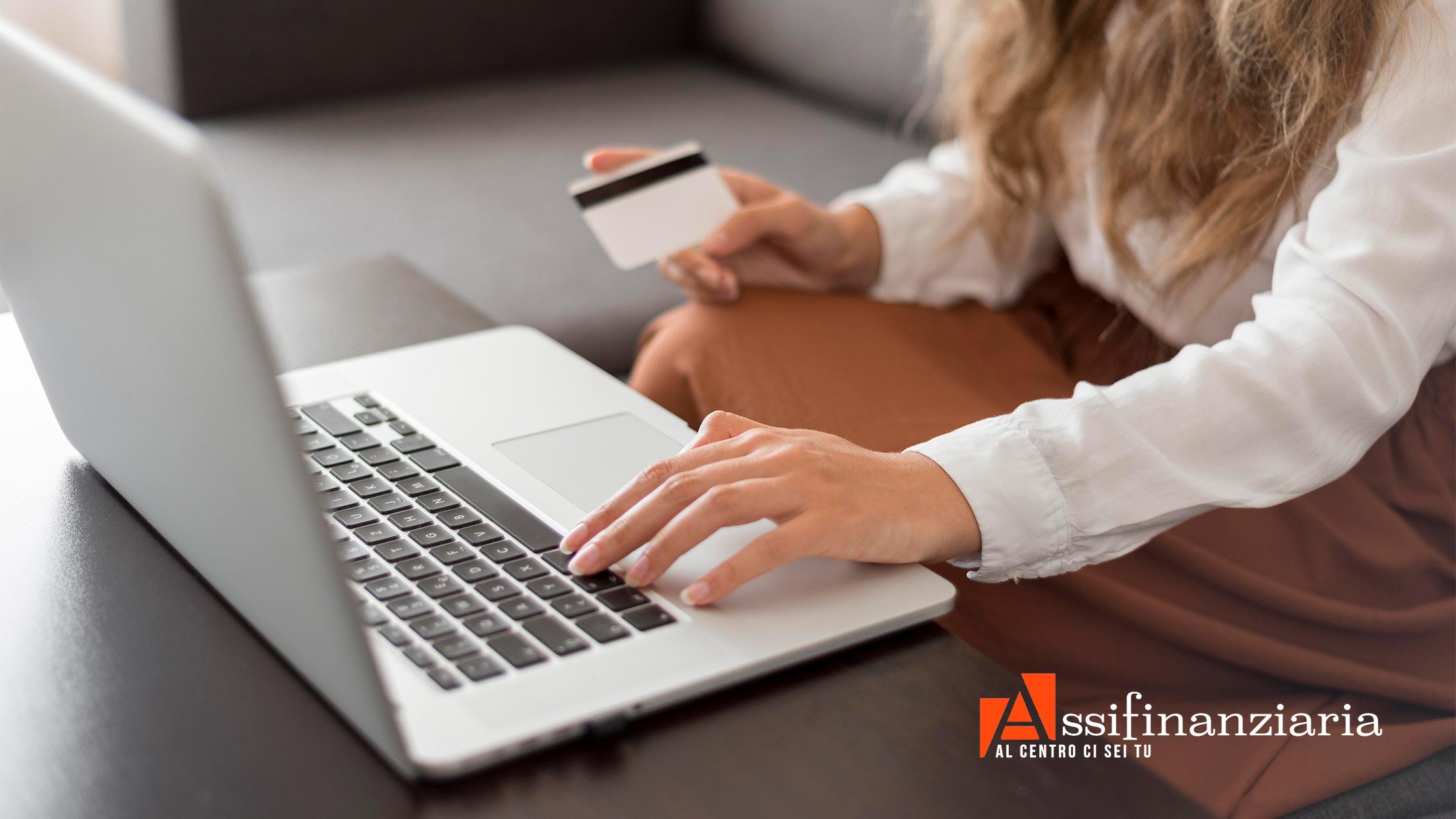 Una donna utilizza un laptop mentre tiene in mano una carta di credito, pronta per gli acquisti del Black Friday